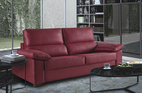 En un salón moderno, un sofá rojo de dos plazas con cojines mullidos se encuentra junto a una estantería y mesas de centro negras.