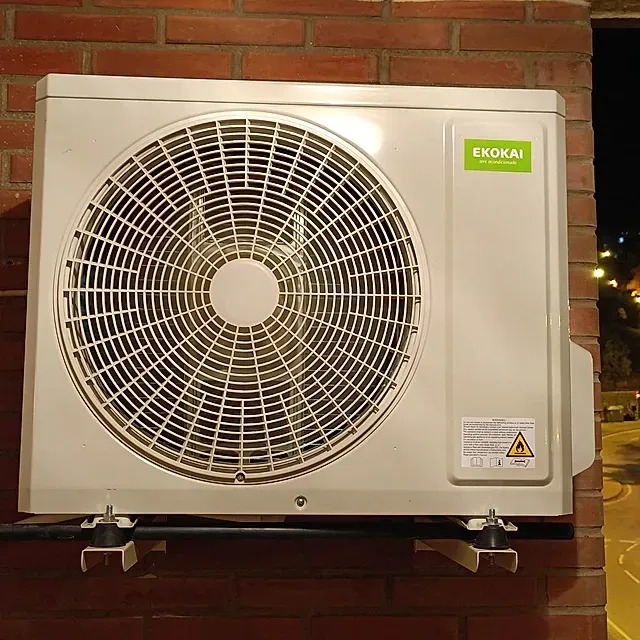 Un ventilador ekokai blanco está montado en una pared de ladrillos.