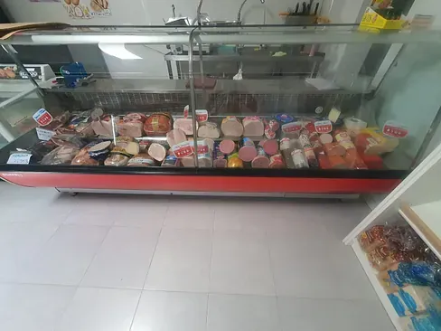 Una vitrina de cristal llena de carnes y quesos en una tienda.