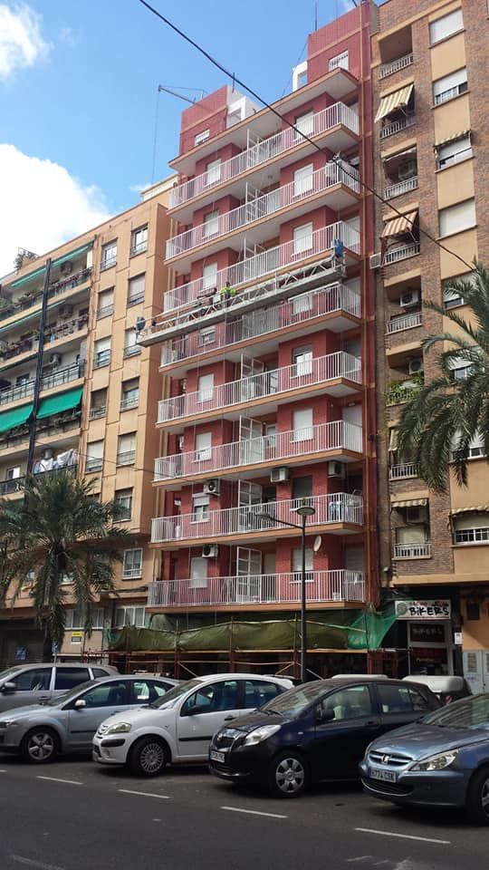 Una fila de coches están aparcados delante de un edificio alto.