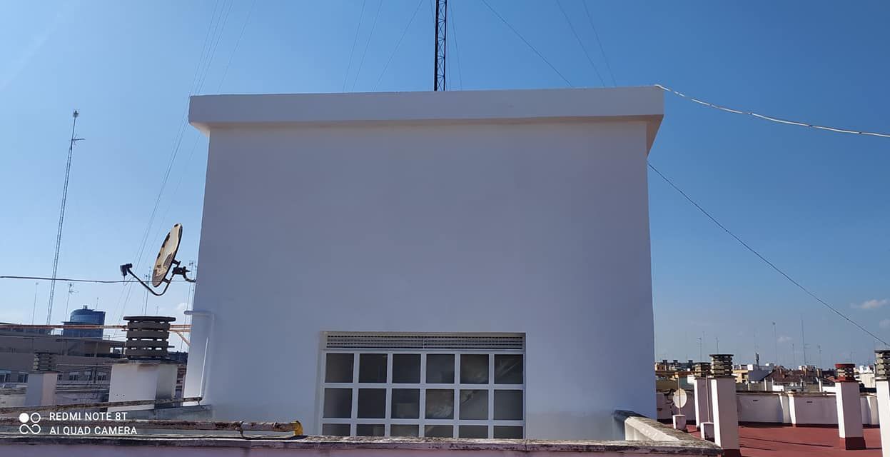 Un edificio blanco con una antena encima.