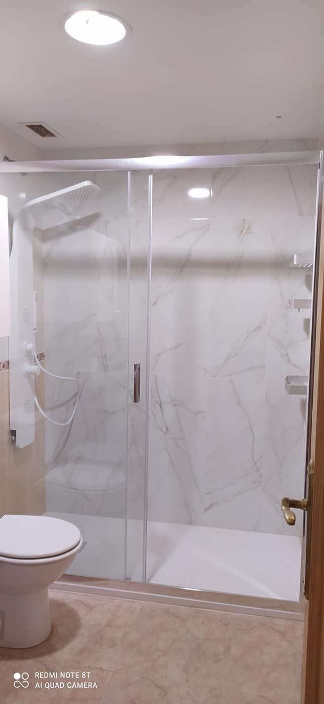 Un baño con inodoro, ducha y puerta corrediza de cristal.