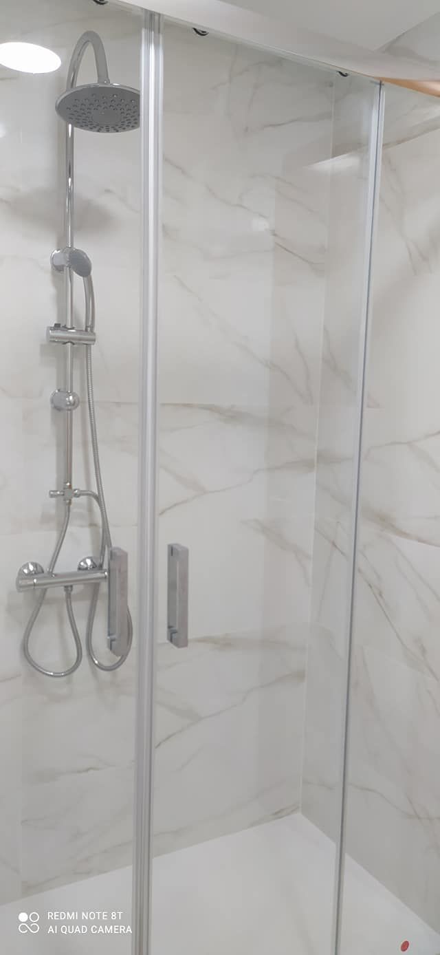Una cabina de ducha con puerta de cristal y cabezal de ducha.