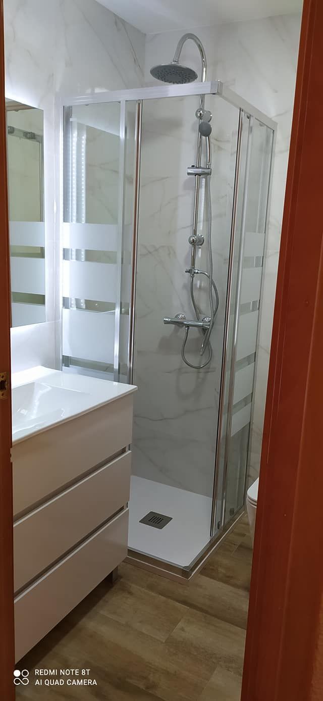 Un baño con ducha, lavabo y espejo.