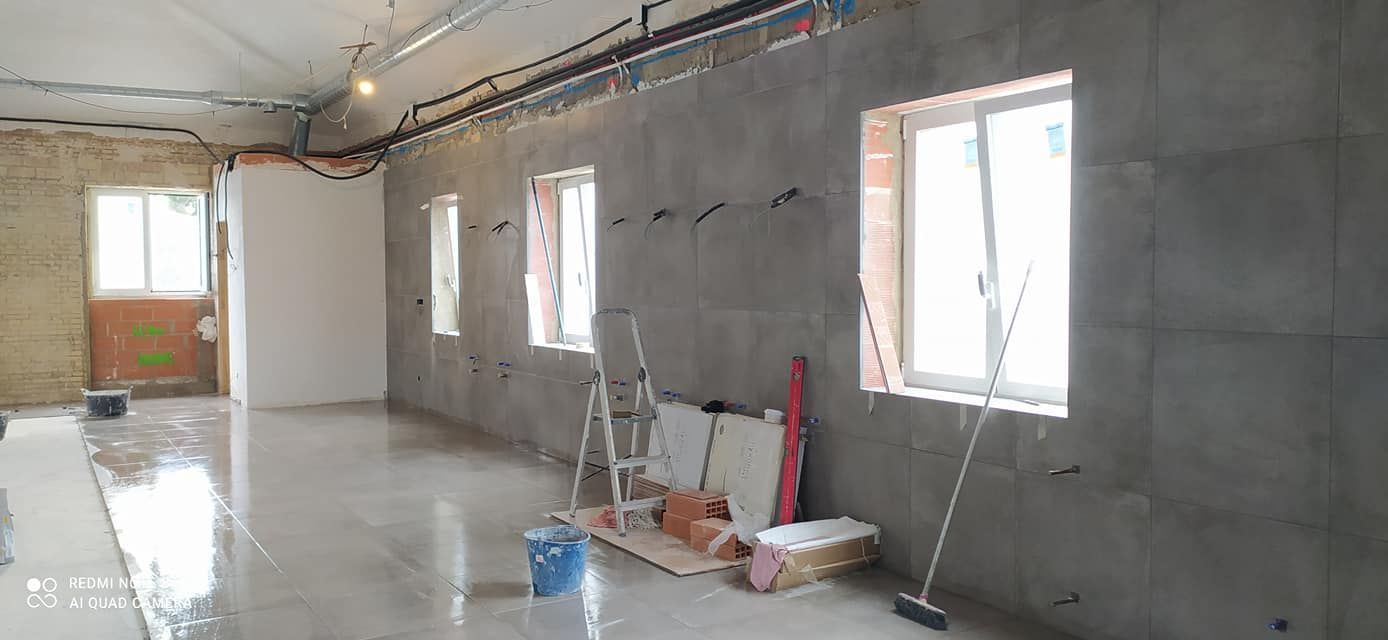 Una habitación vacía con una escalera y una escoba en el suelo.