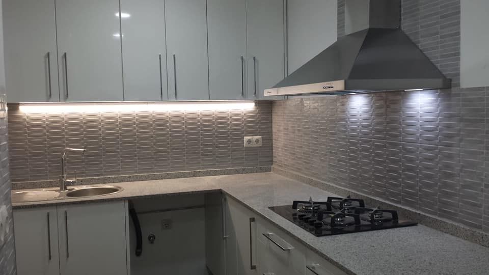 Una cocina con gabinetes blancos y un horno de estufa.