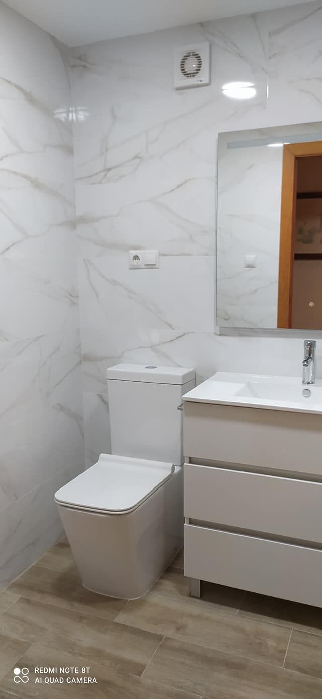 Un baño con inodoro, lavabo y espejo.