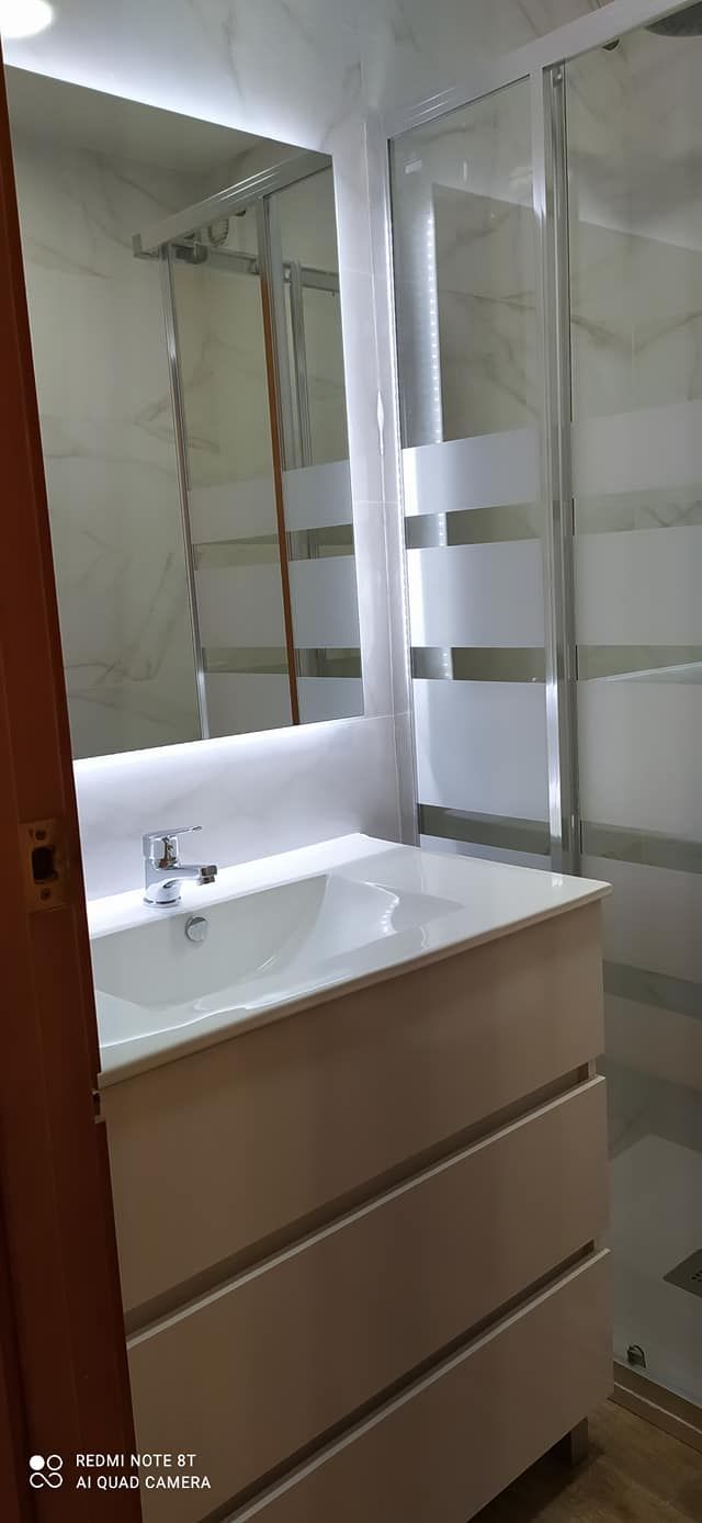 Un baño con lavabo, espejo y ducha.