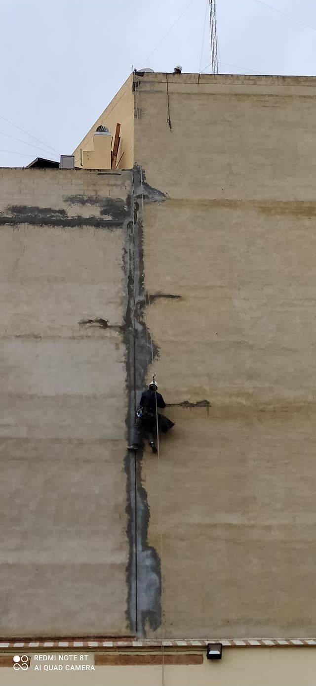Un hombre está trabajando en el costado de un edificio.