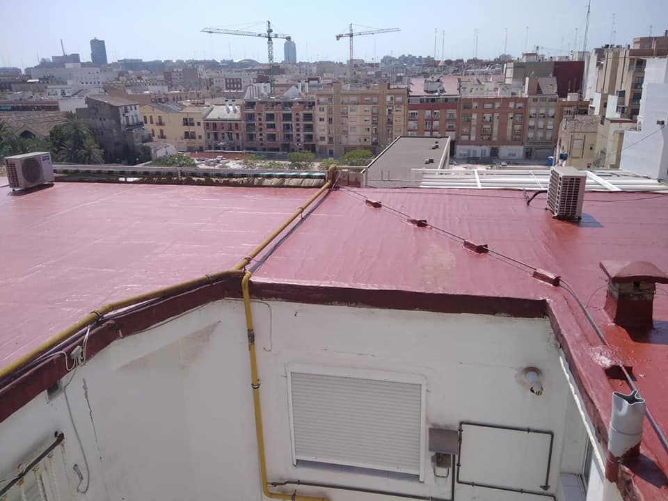 Un edificio con techo rojo y una ciudad al fondo.