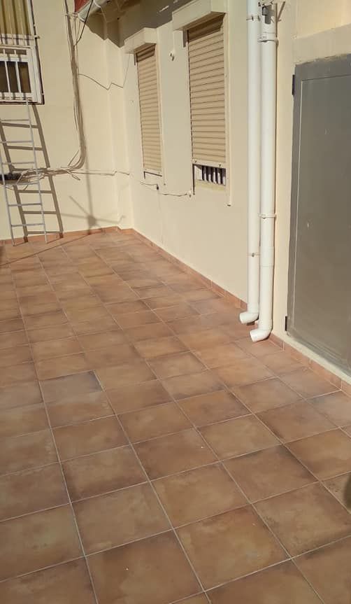 Una escalera se encuentra en el costado de un edificio, al lado de un piso de baldosas.