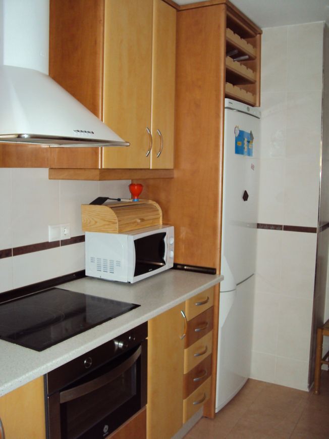 Una cocina con gabinetes de madera y microondas.