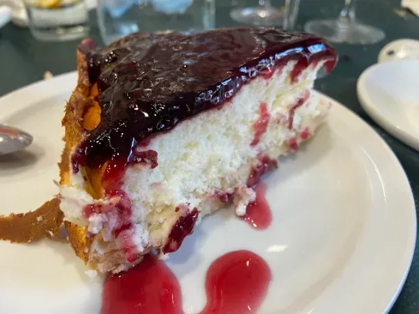 Una rebanada de tarta de queso con salsa de bayas en un plato blanco.