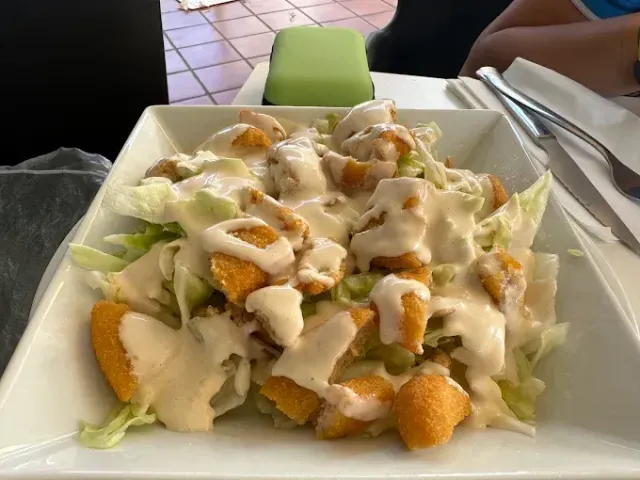 Un plato de comida con pollo y lechuga sobre una mesa.