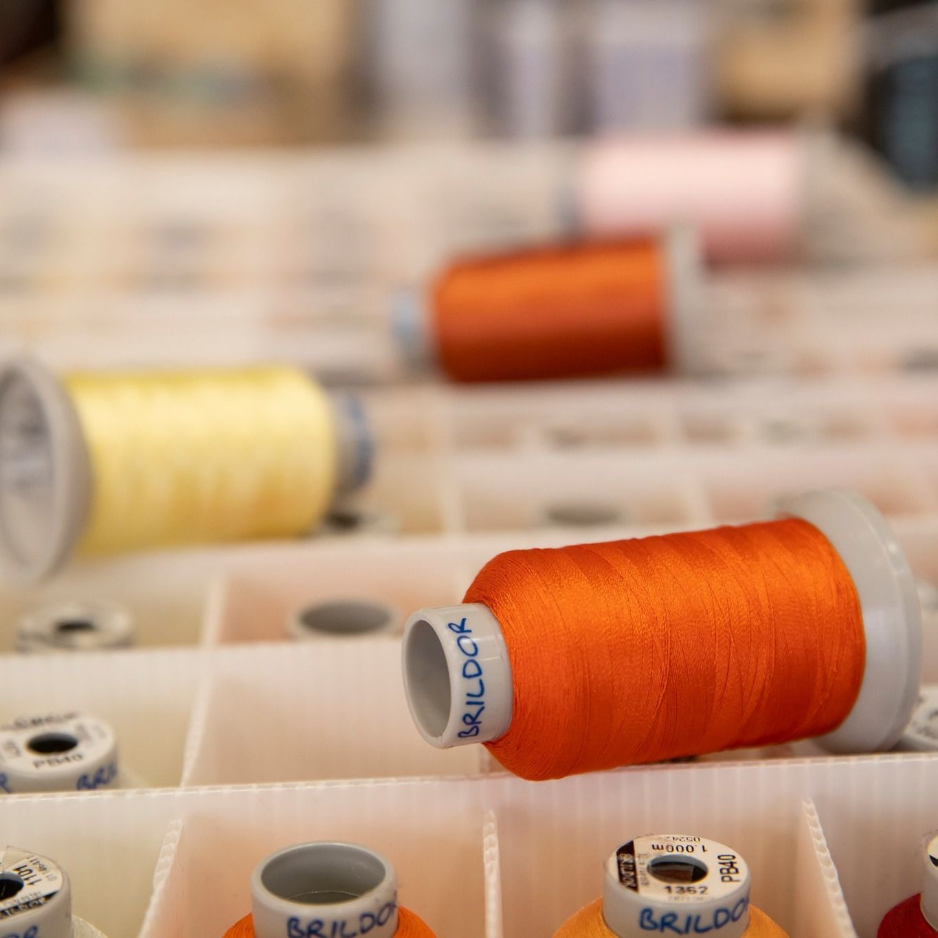 Un carrete de hilo de coser naranja con la palabra brildor en él