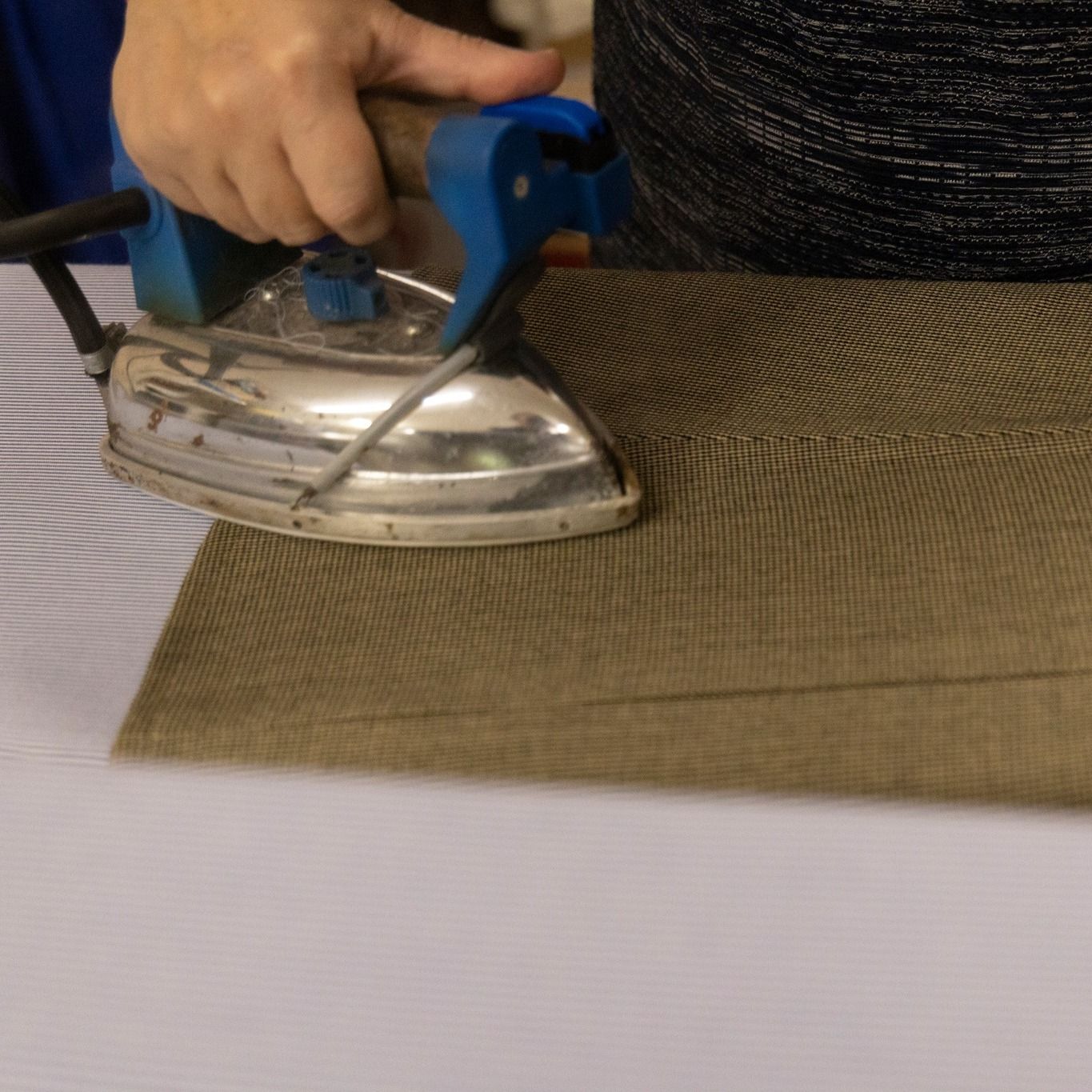 Una persona está planchando un trozo de tela sobre una mesa.