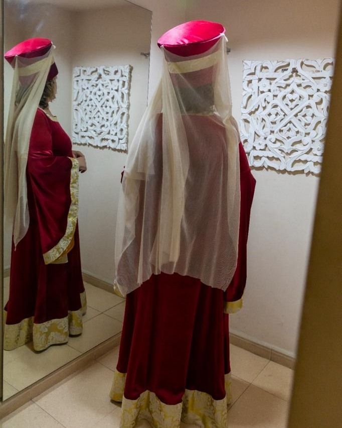 Una mujer con un vestido rojo está parada frente a un espejo.