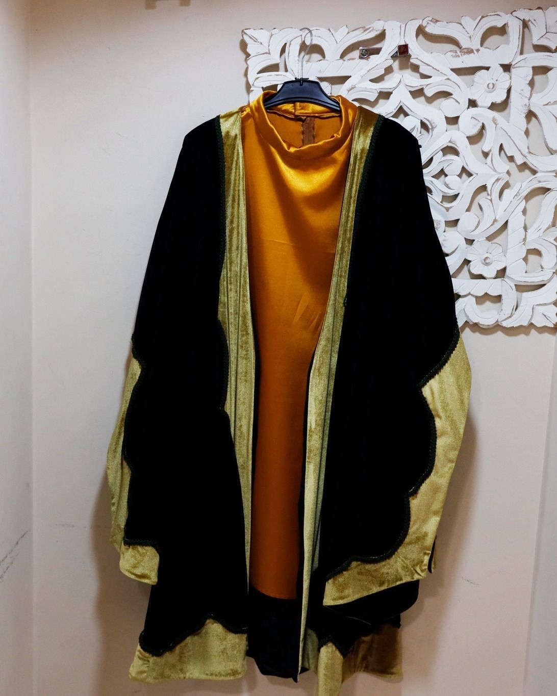 Una chaqueta negra y dorada está colgada en una percha