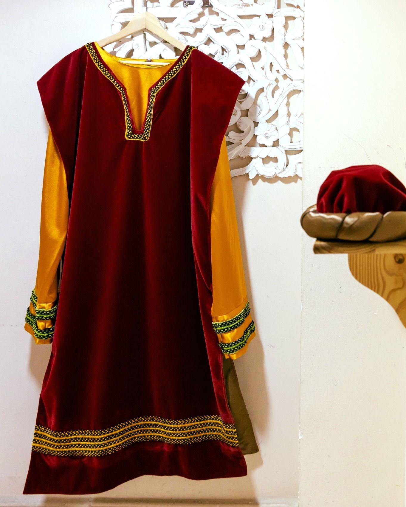 Un vestido rojo y amarillo está colgado en una percha.