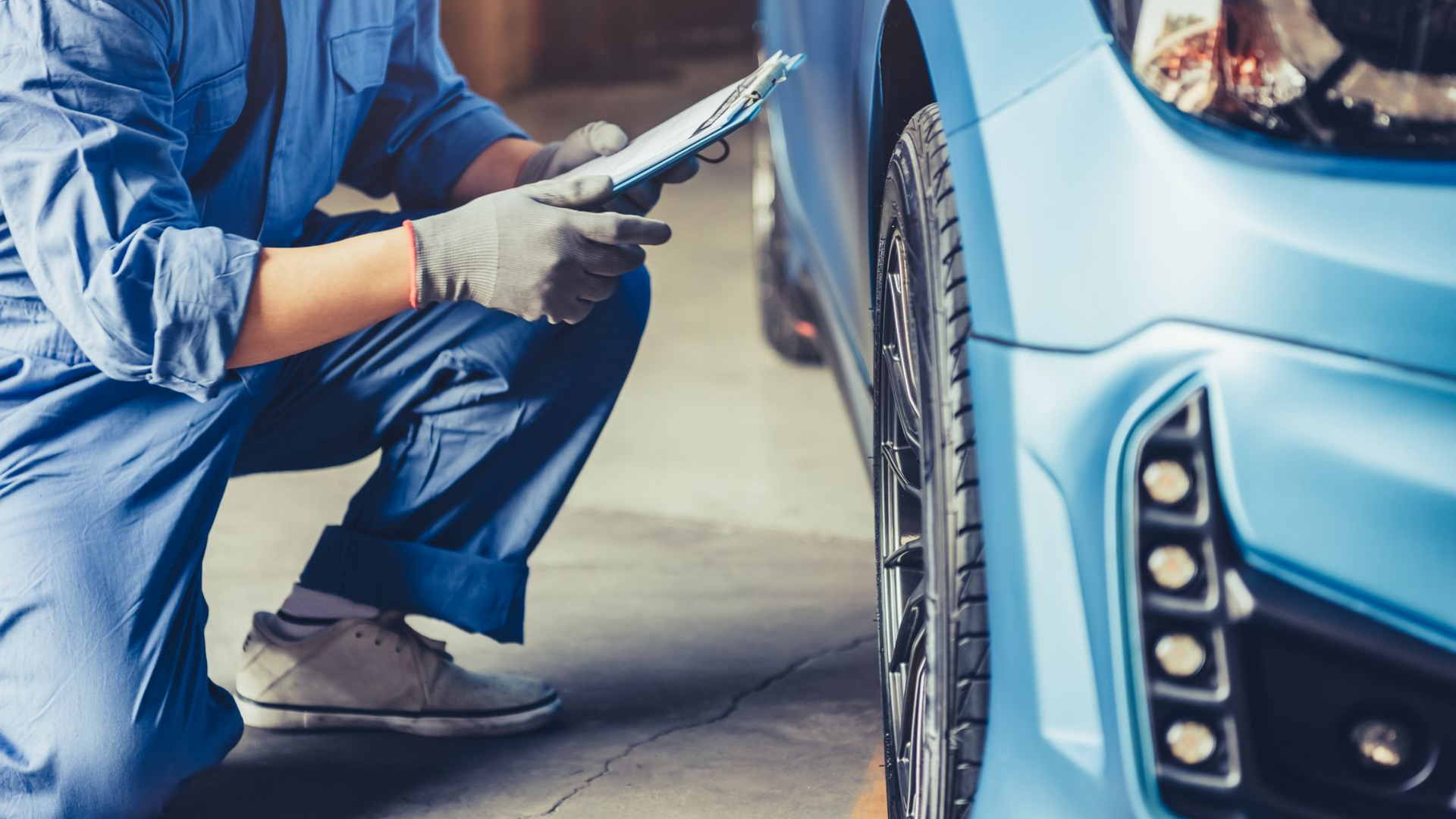 Un mécanicien inspecte l'extérieur d'une voiture bleue