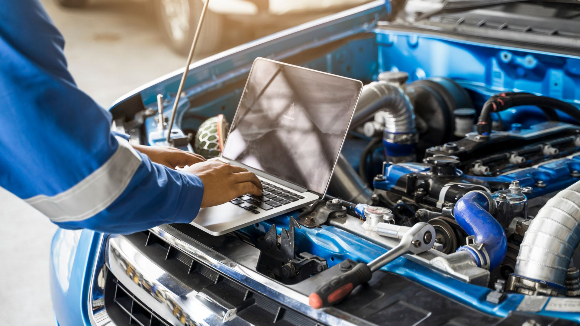 Mécanicien se servant d'un ordinateur pour le diagnostic d'une voiture au capot ouvert