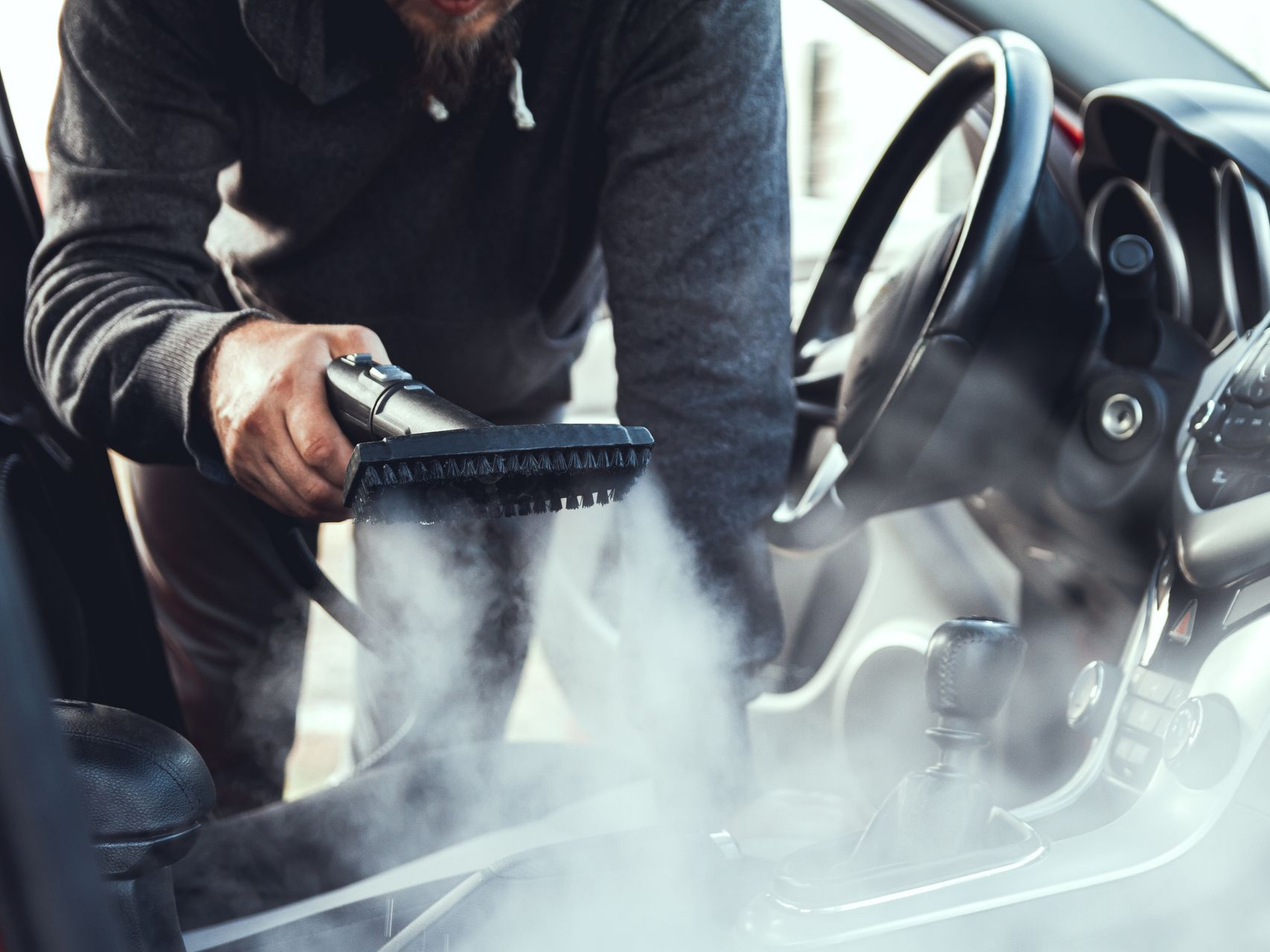 Un homme nettoie l'intérieur d'une voiture à la vapeur