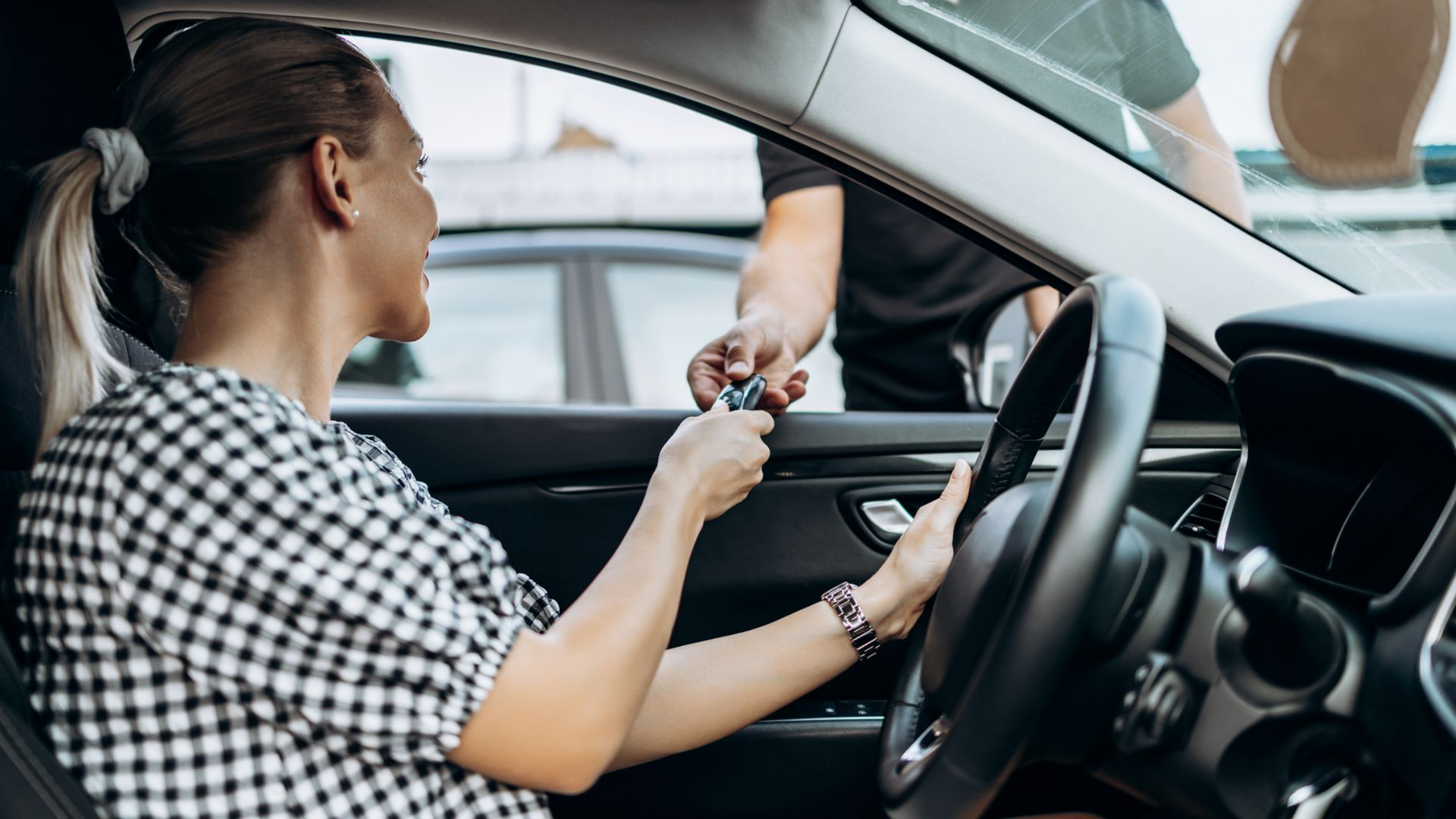 Femme de dos assise dans une voiture reçoit les clés de la part du vendeur