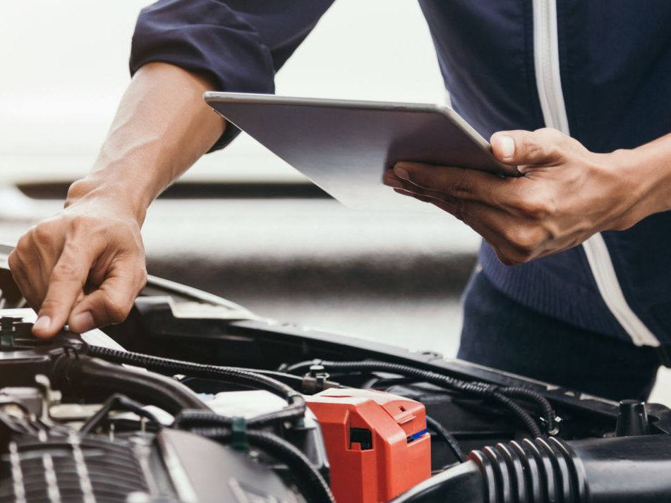 Un mécanicien équipé d'une tablette inspecte un moteur de voiture