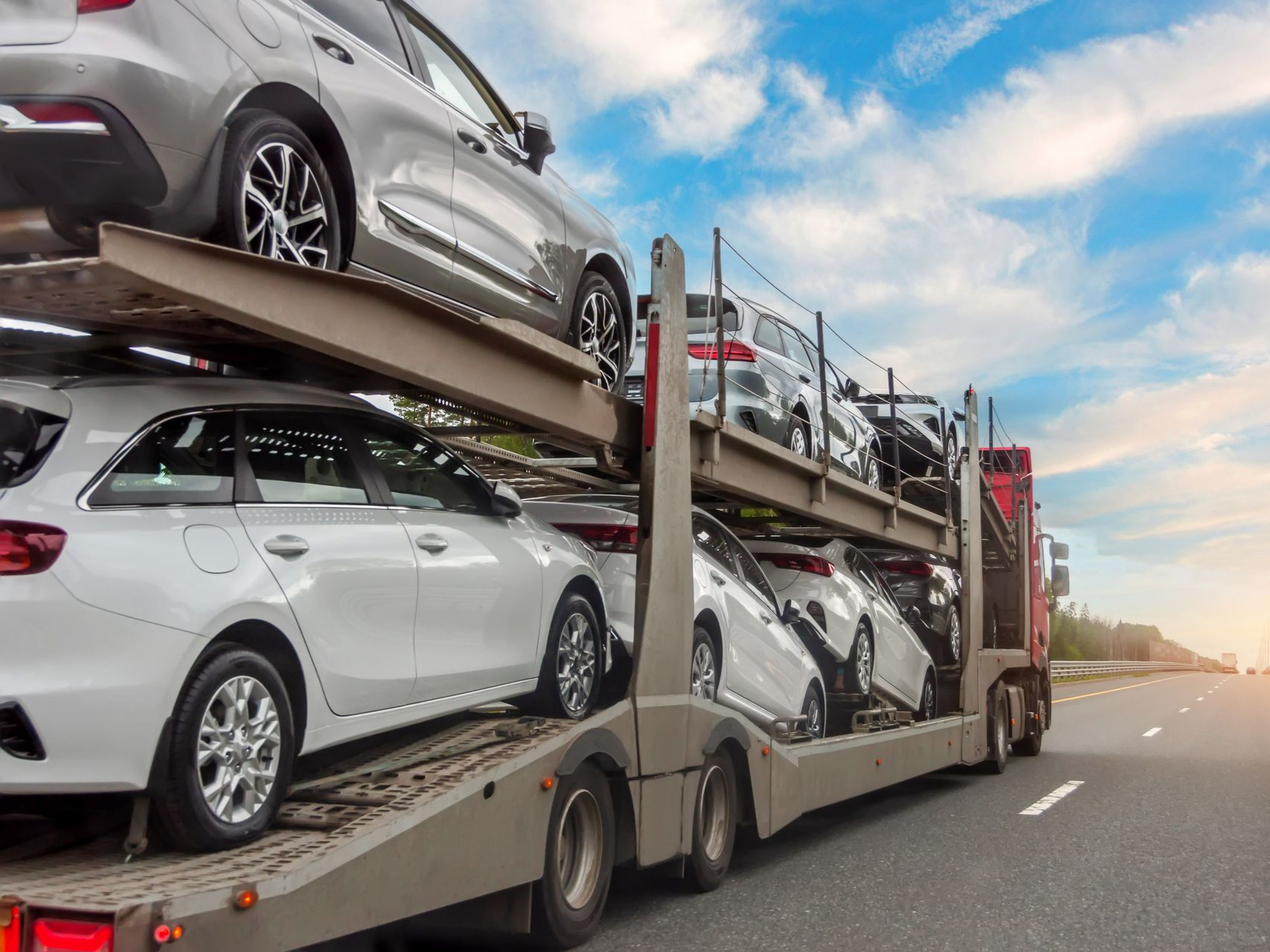 Des voitures blanches et grises transportées par un camion