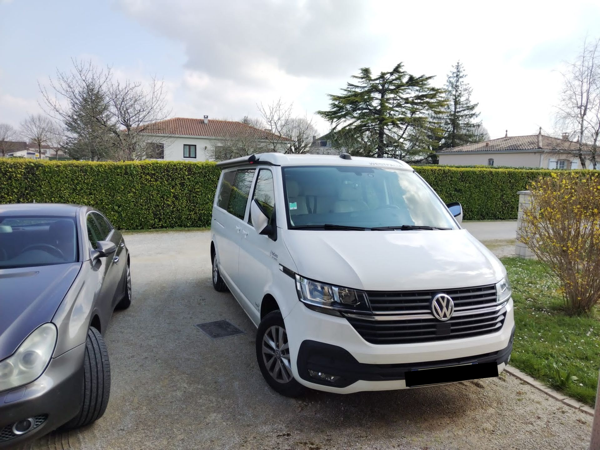 Un van blanc garé à côté d'une Mercedes