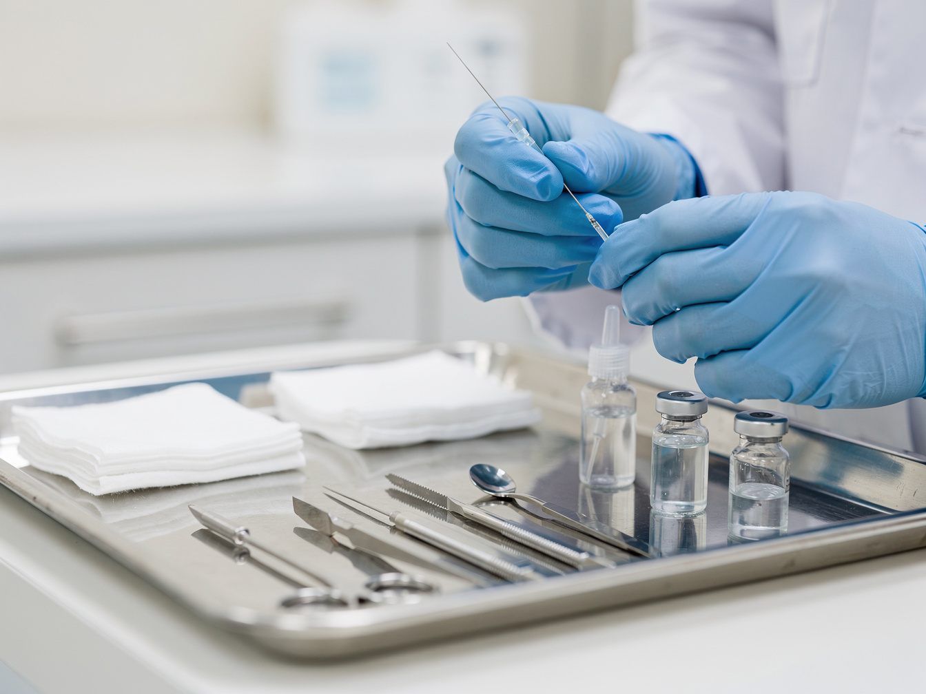 Gloved hands preparing a fine injection needle