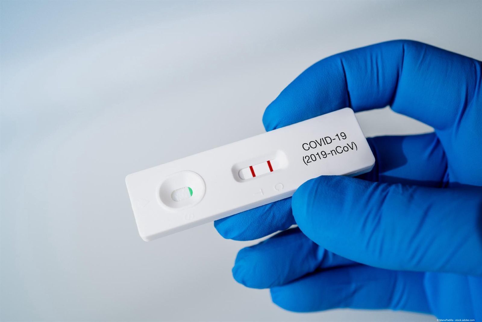 Behandschuhte Hand hält einen Corona-Schnelltest