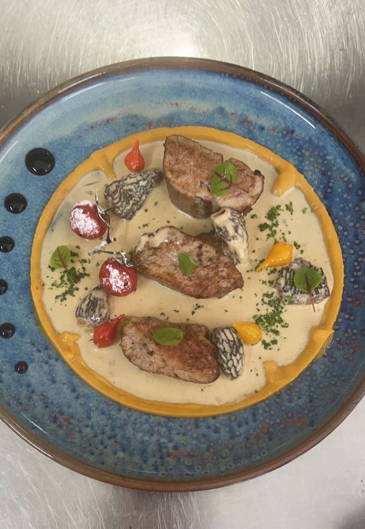 Plat de viande en sauce dans une assiette bleue.