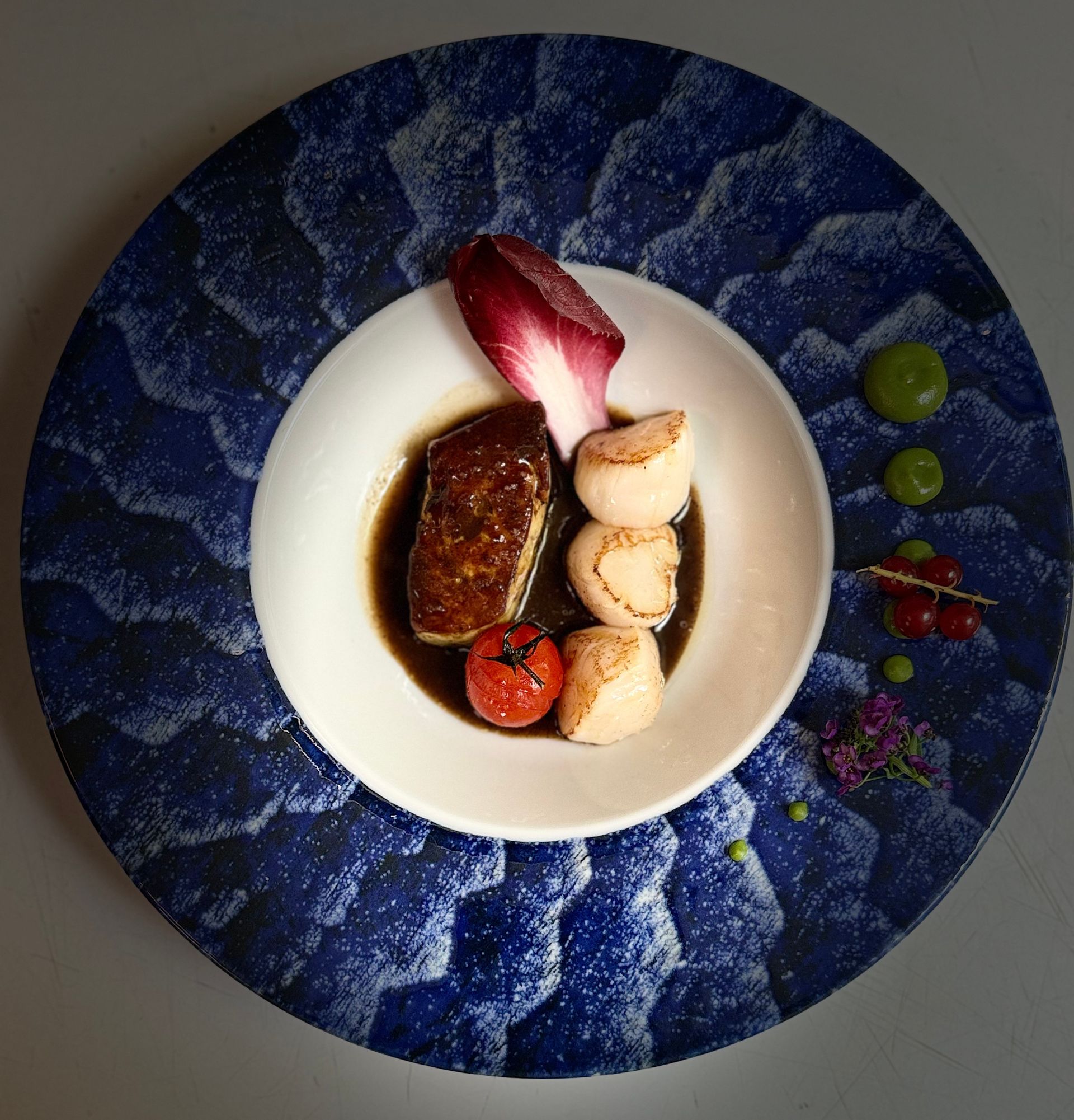 Plat de viande en sauce dans un petit bol blanc posé sur une assiette bleue.