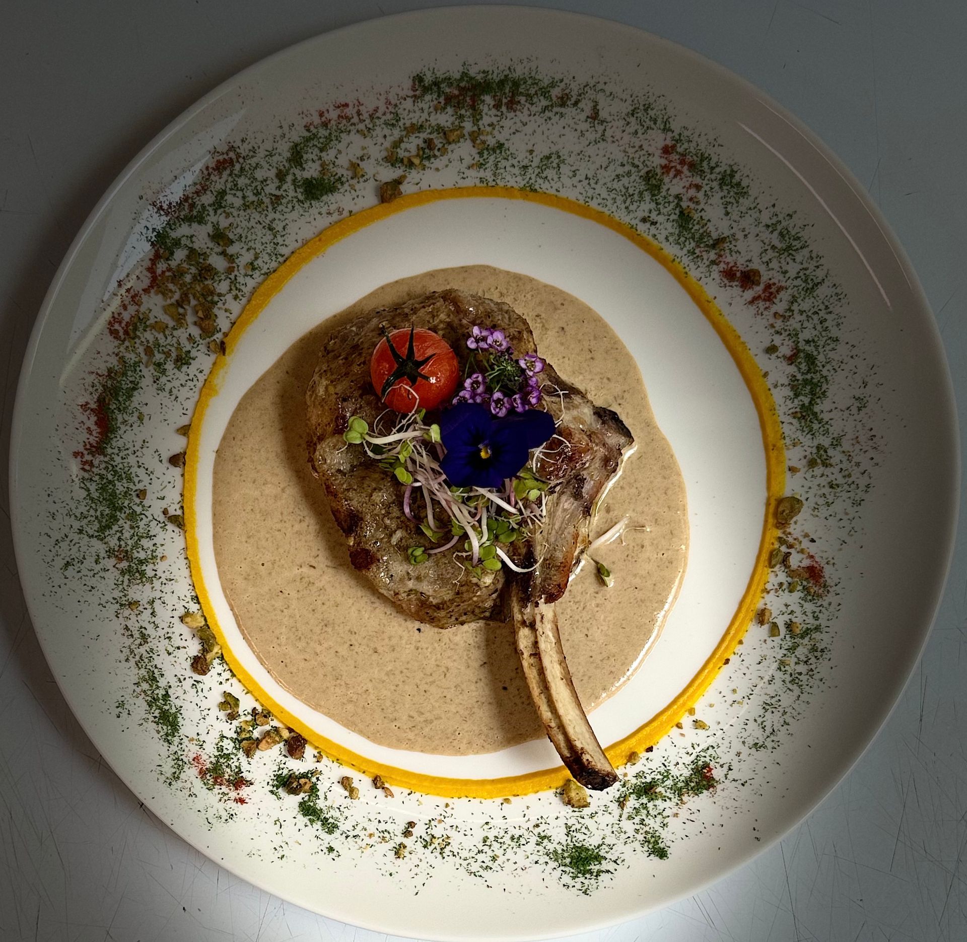 Plat de viande en sauce avec une tomate dans une assiette blanche.