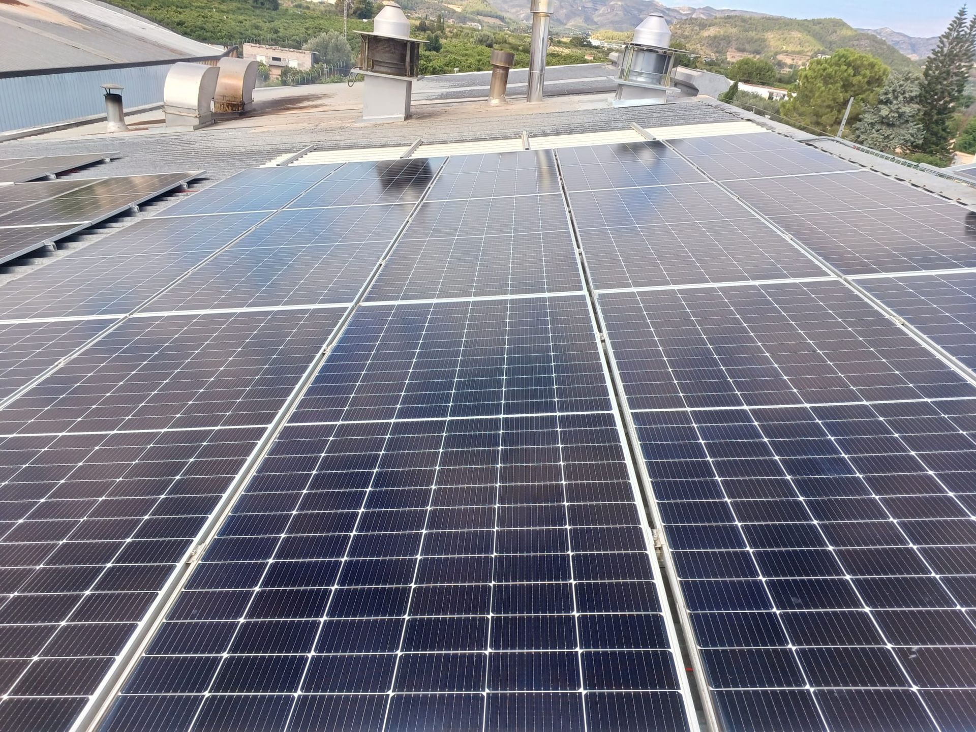 Paneles solares en el tejado de un edificio, reflejando el cielo.