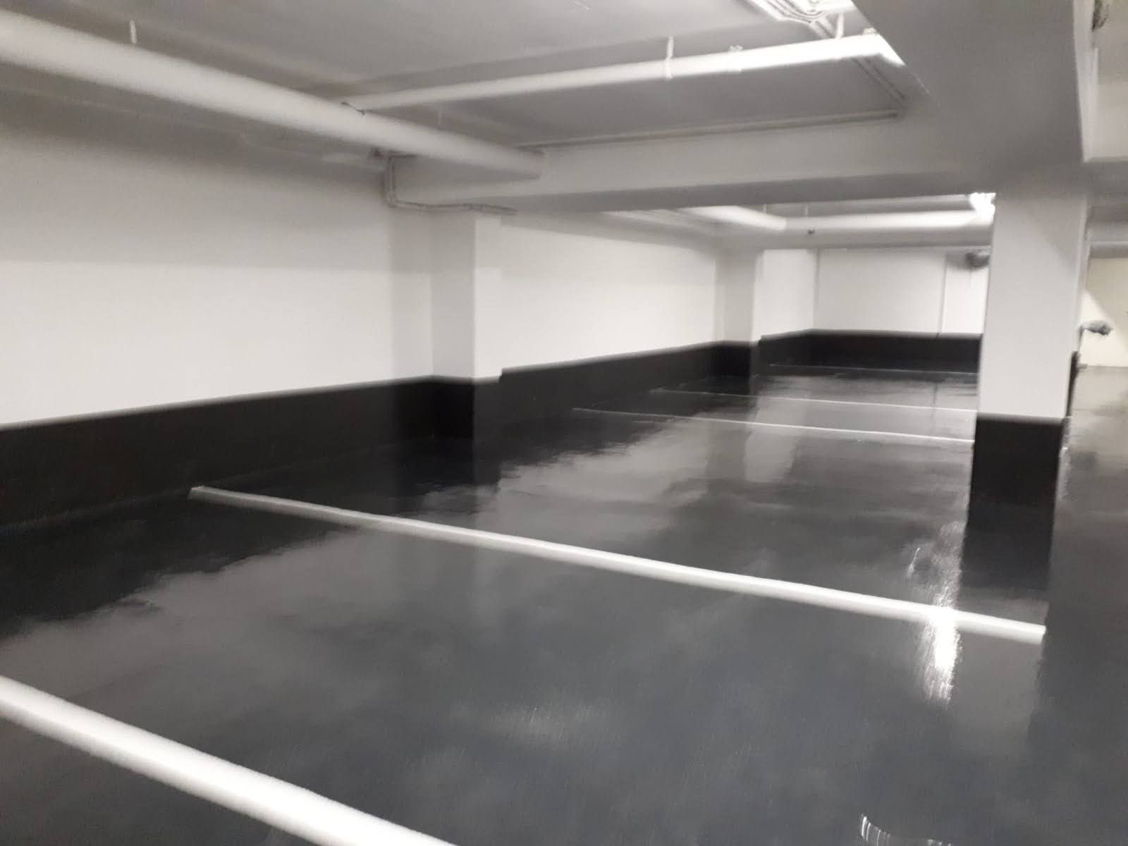 Estacionamiento gris y negro con líneas, vigas y columnas blancas.