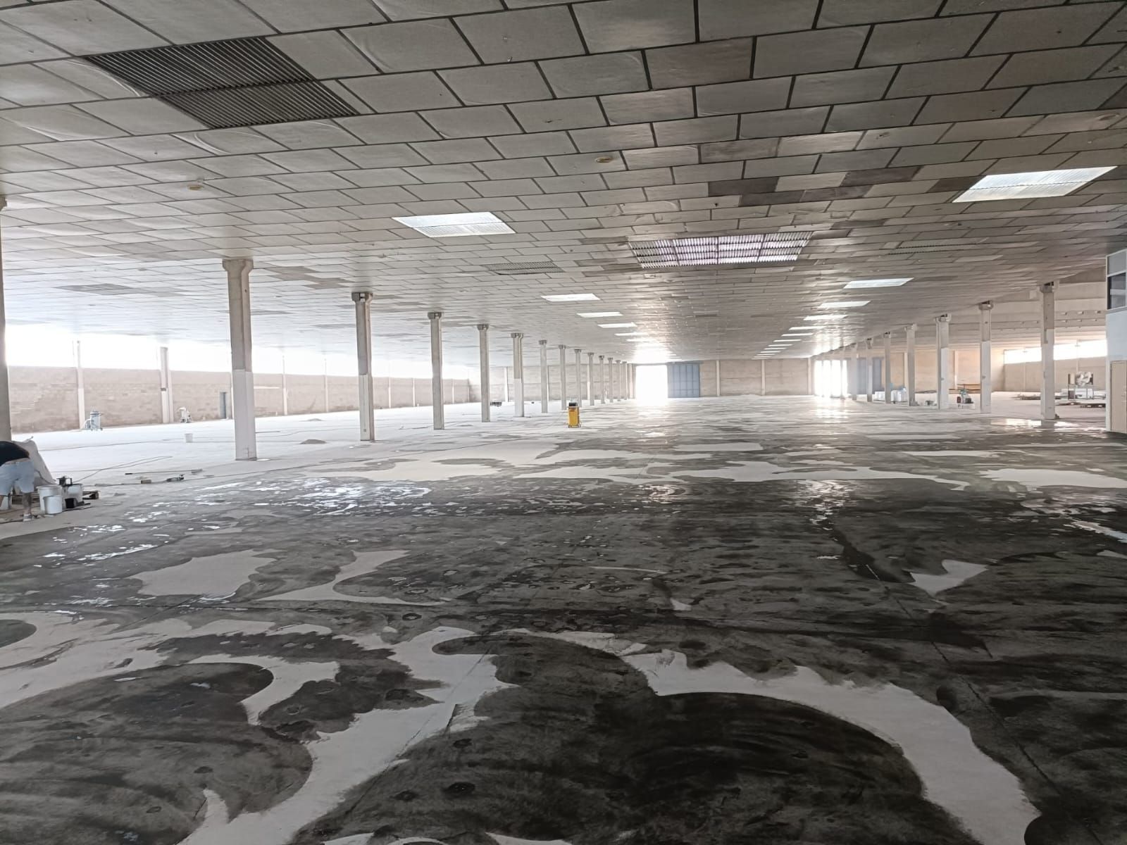 Espacio industrial vacío e inundado con numerosos pilares de soporte y placas de techo.