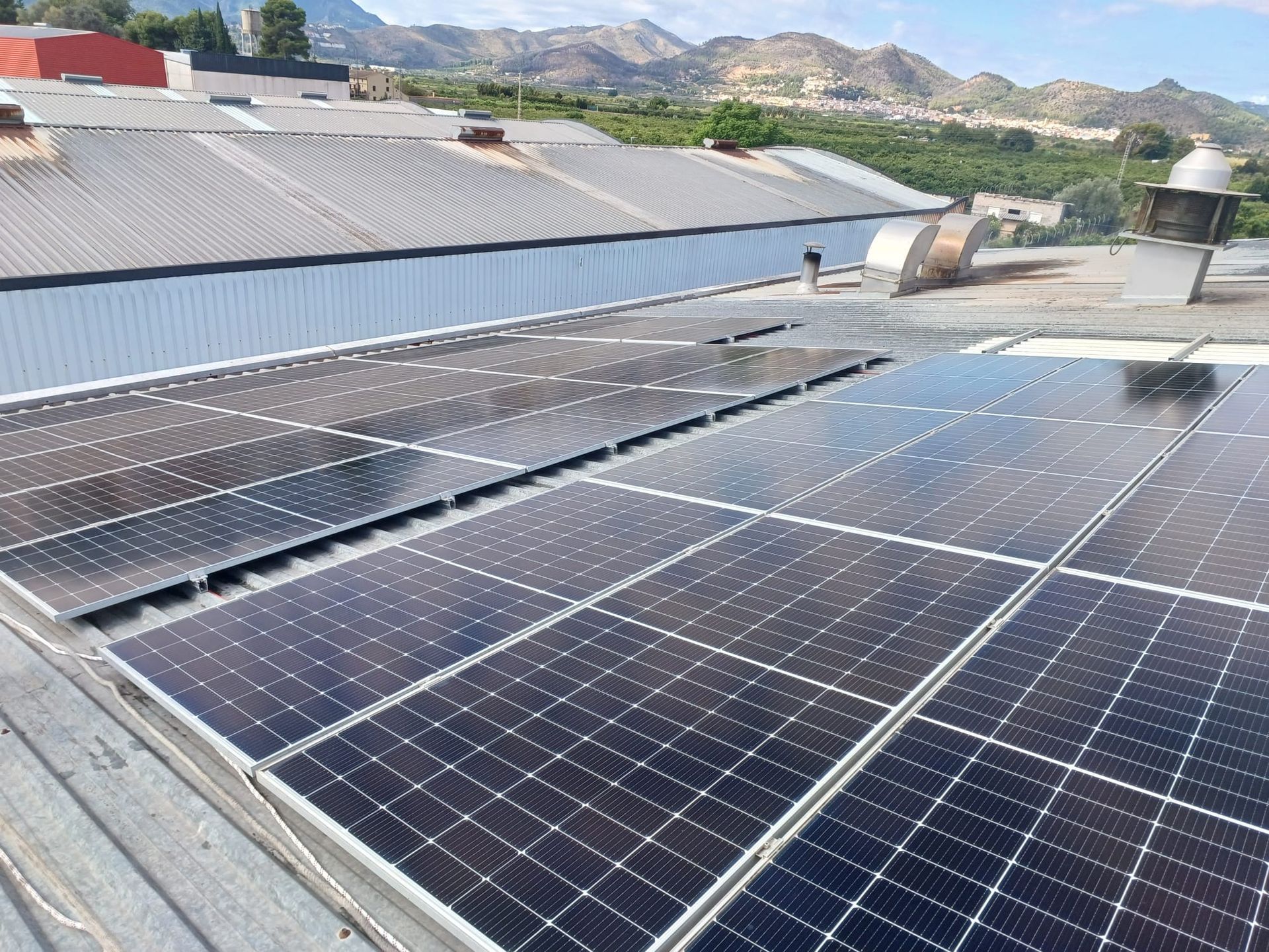Paneles solares sobre un techo de metal, con montañas al fondo.