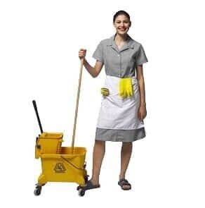 Mulher com uniforme de limpeza segurando um esfregão ao lado de um carrinho de limpeza amarelo.