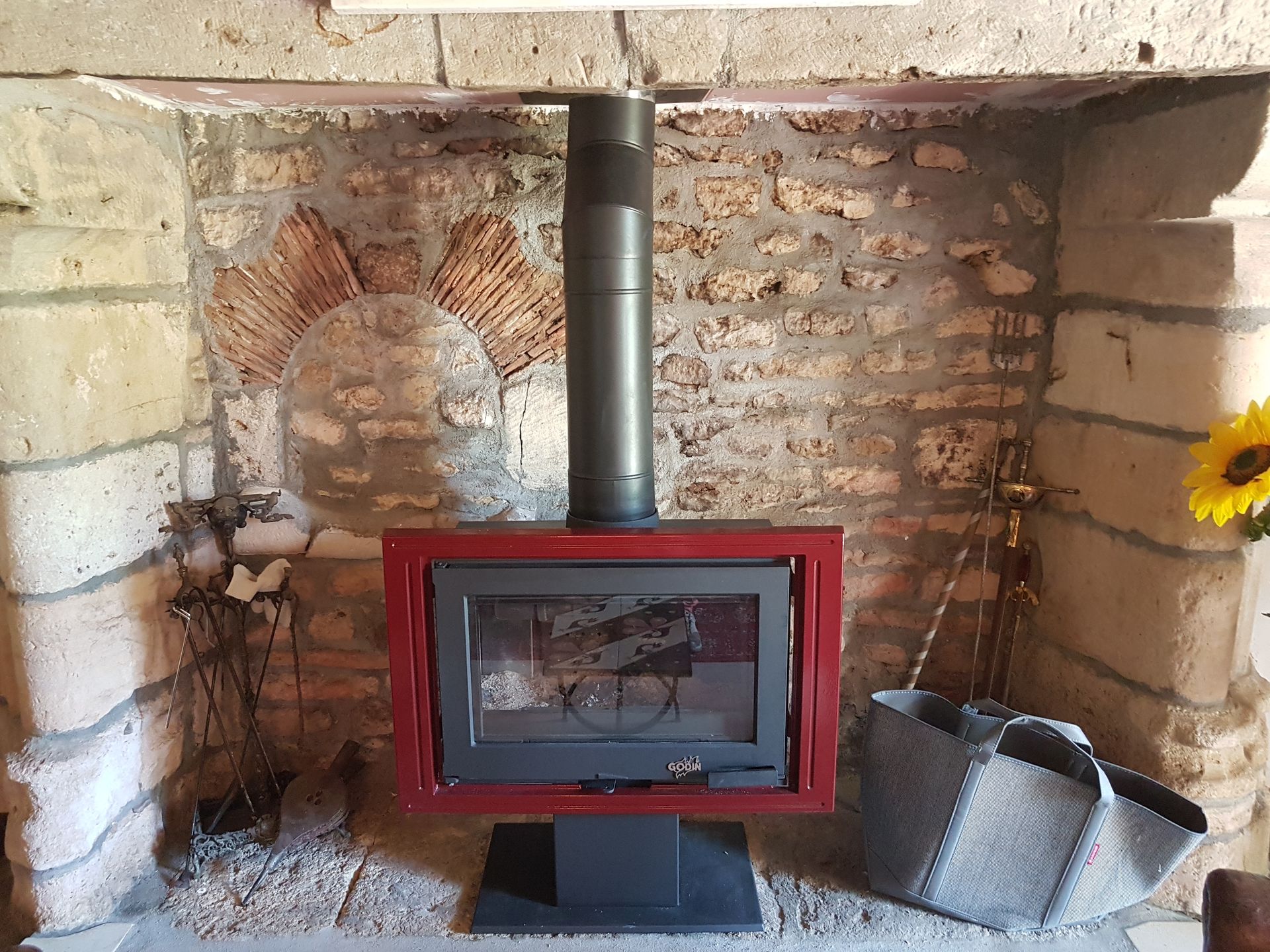 Poêle à bois rouge, cheminée en pierre