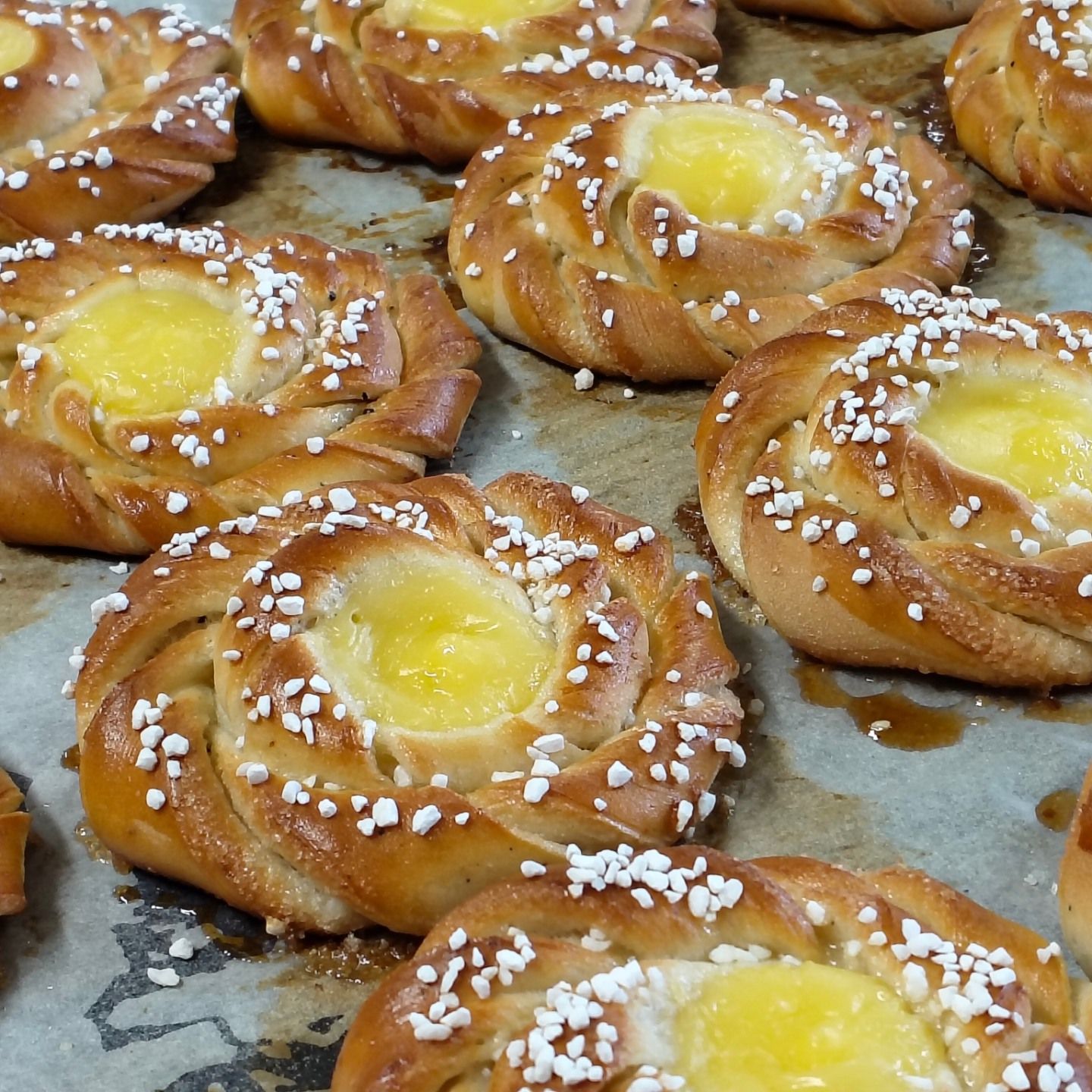 Bricka med gyllene bakverk med gula mittpunkter och pärlsockerströssel på bakplåtspapper