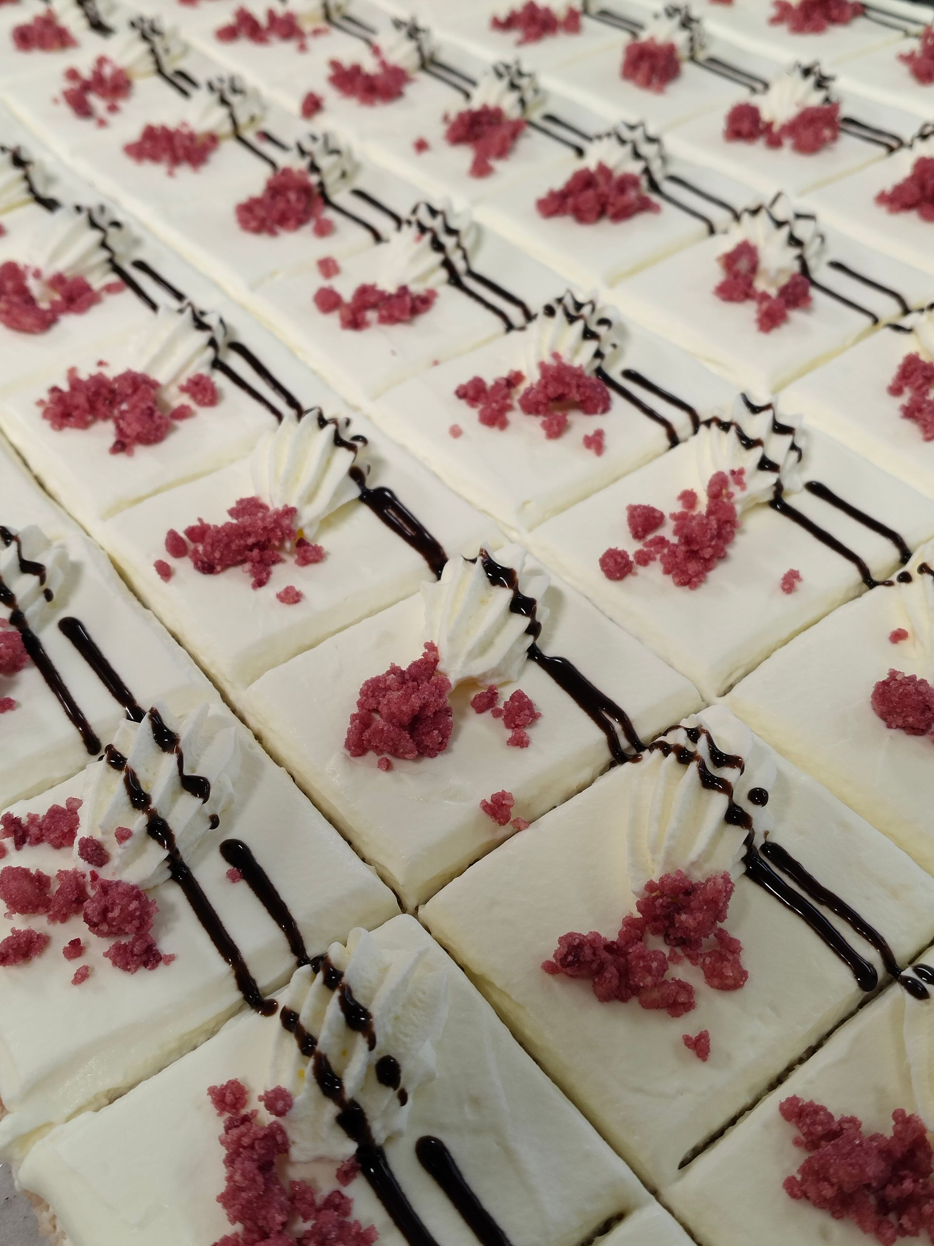 Rader av vita frostade dessertrutor med mörkt duggregn och rosa strössel