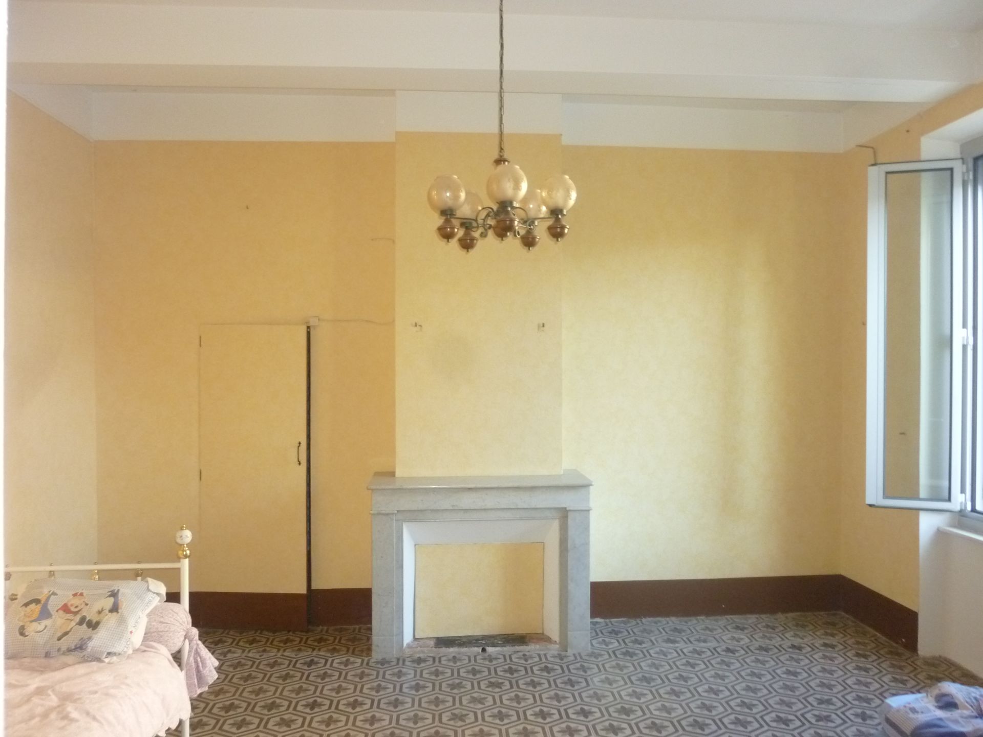 Cheminée sur un mur jaune à côté d'une porte et un luminaire au plafond