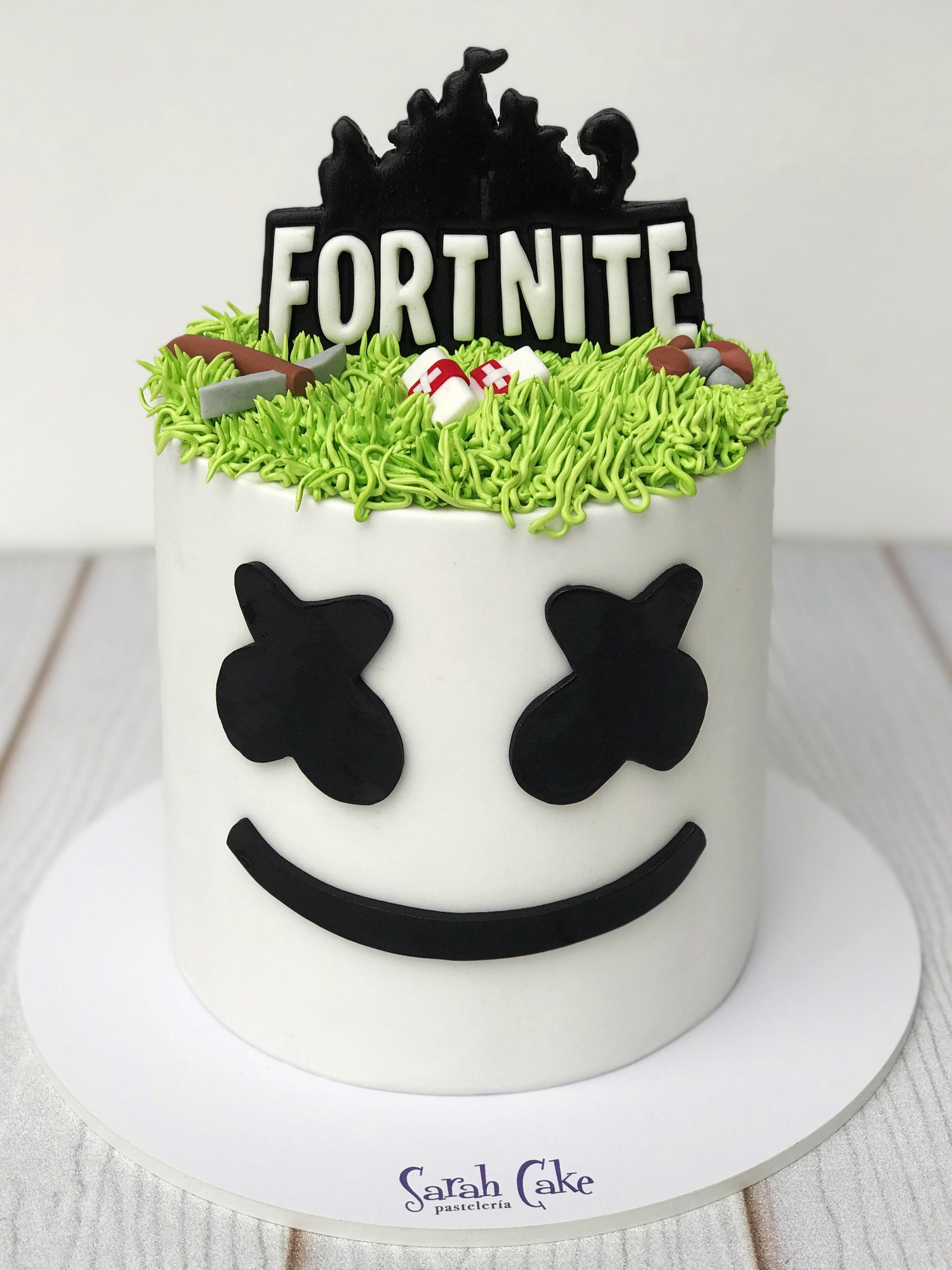 Un pastel blanco con una cara de malvavisco y la palabra Fortnite encima.