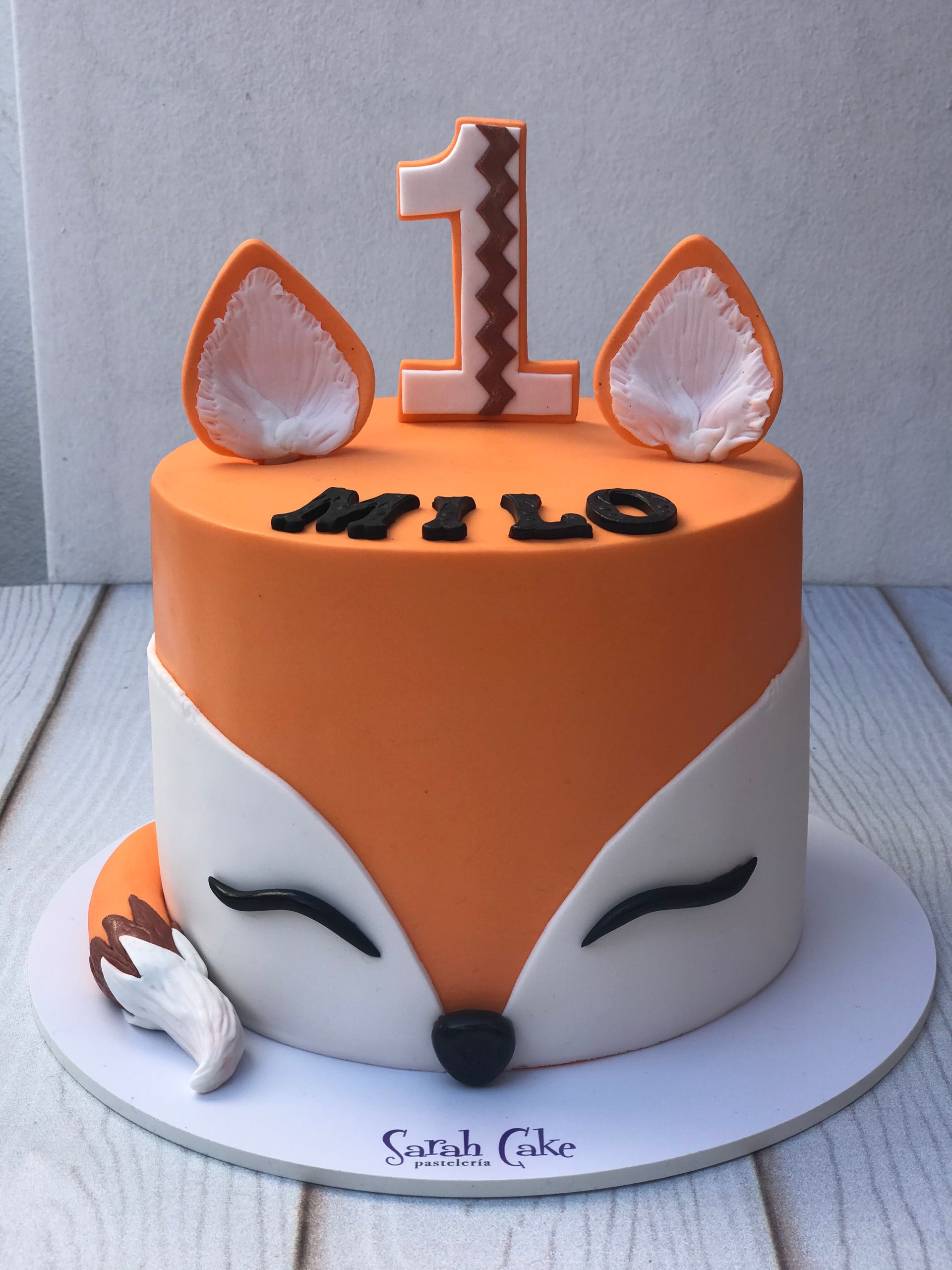 Un pastel con una cara de zorro y el número 1 en la parte superior.