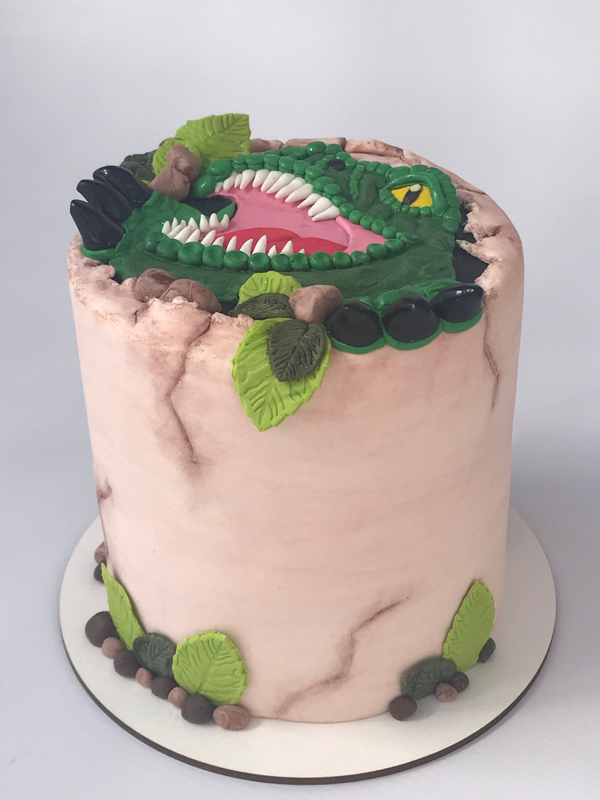 Un pastel con un dinosaurio encima.