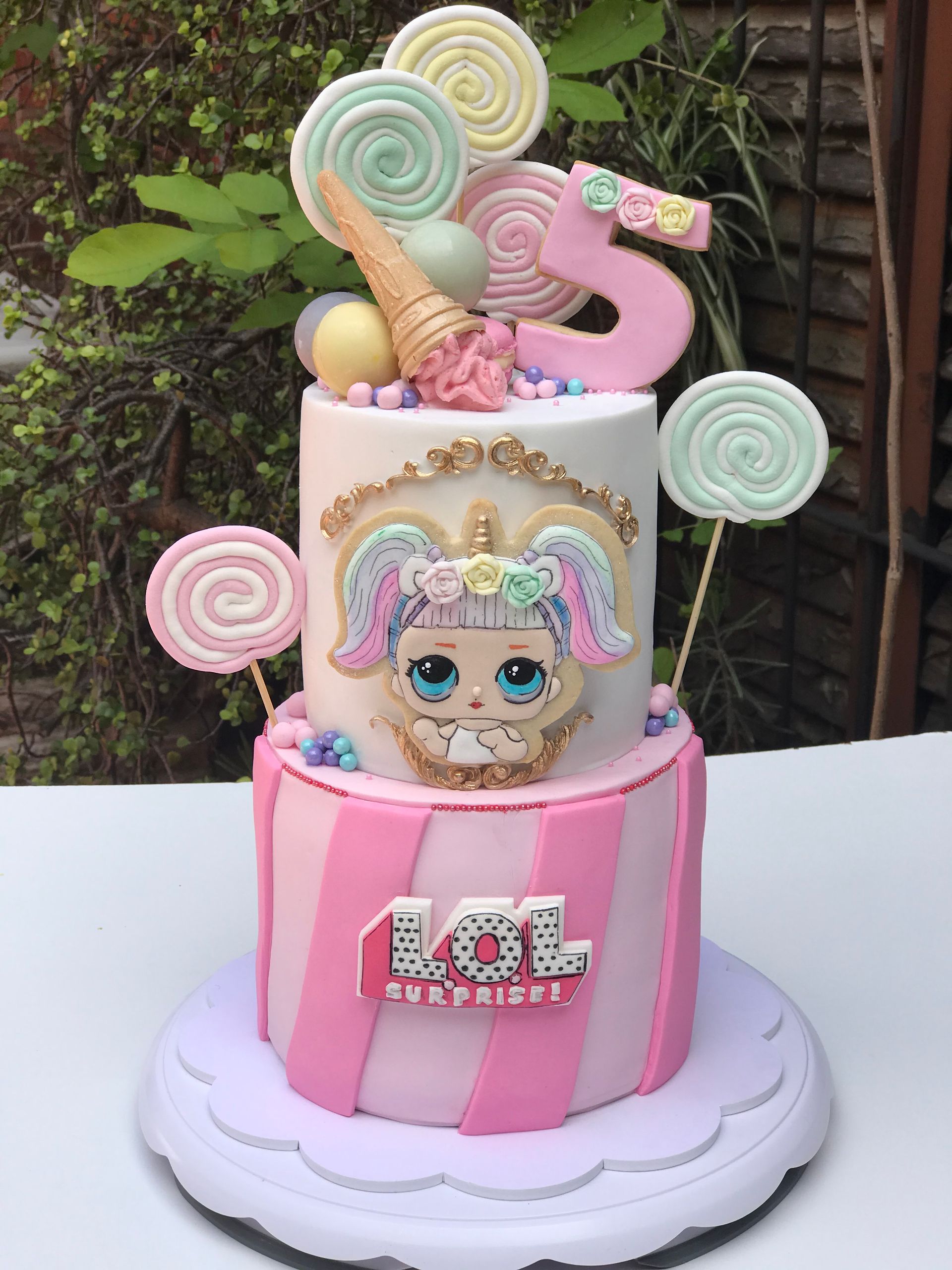 Un pastel sorpresa rosa y blanco con piruletas encima.