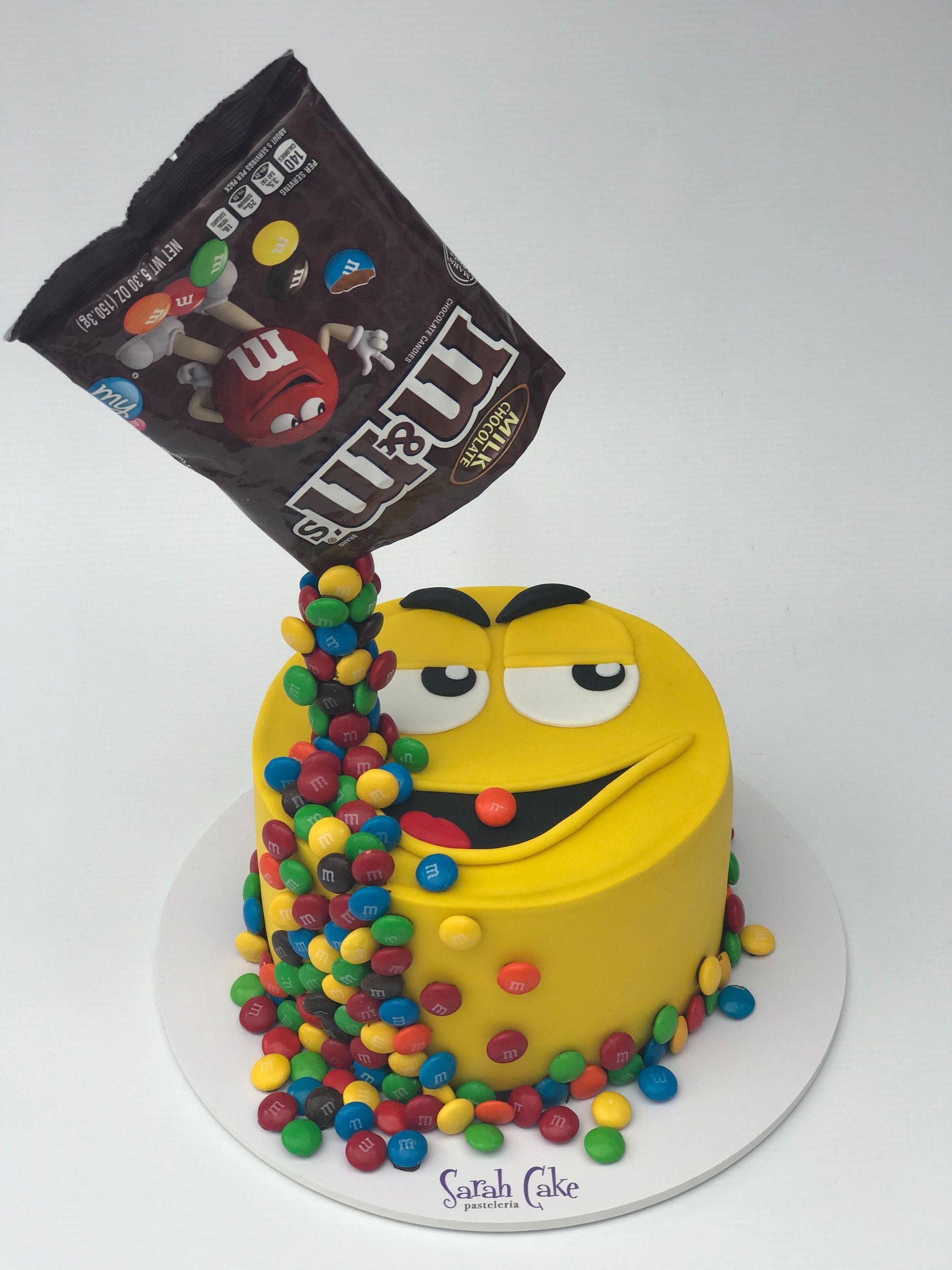 Un pastel amarillo con M&M's saliendo de una bolsa
