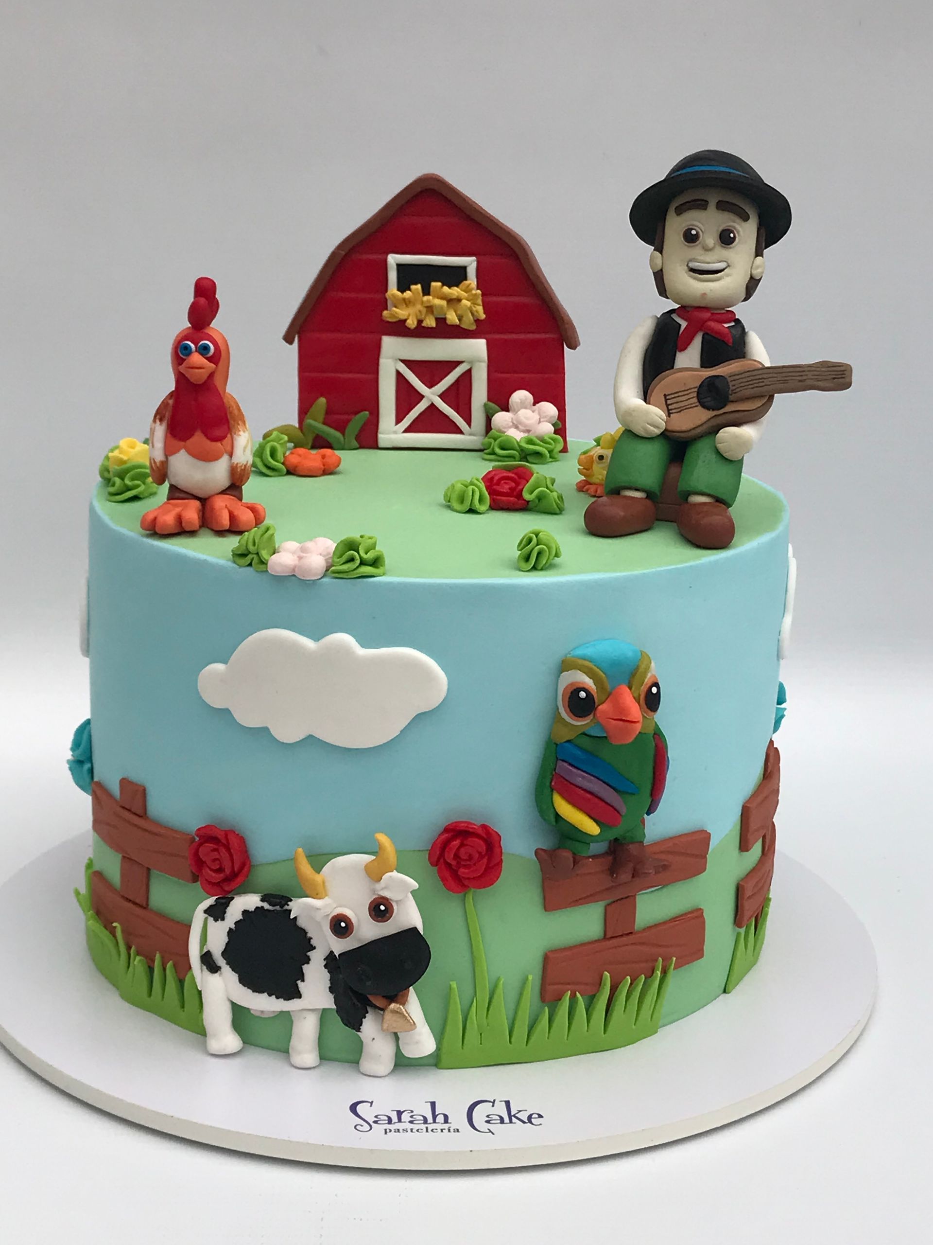 Un pastel con un hombre tocando una guitarra y animales encima.